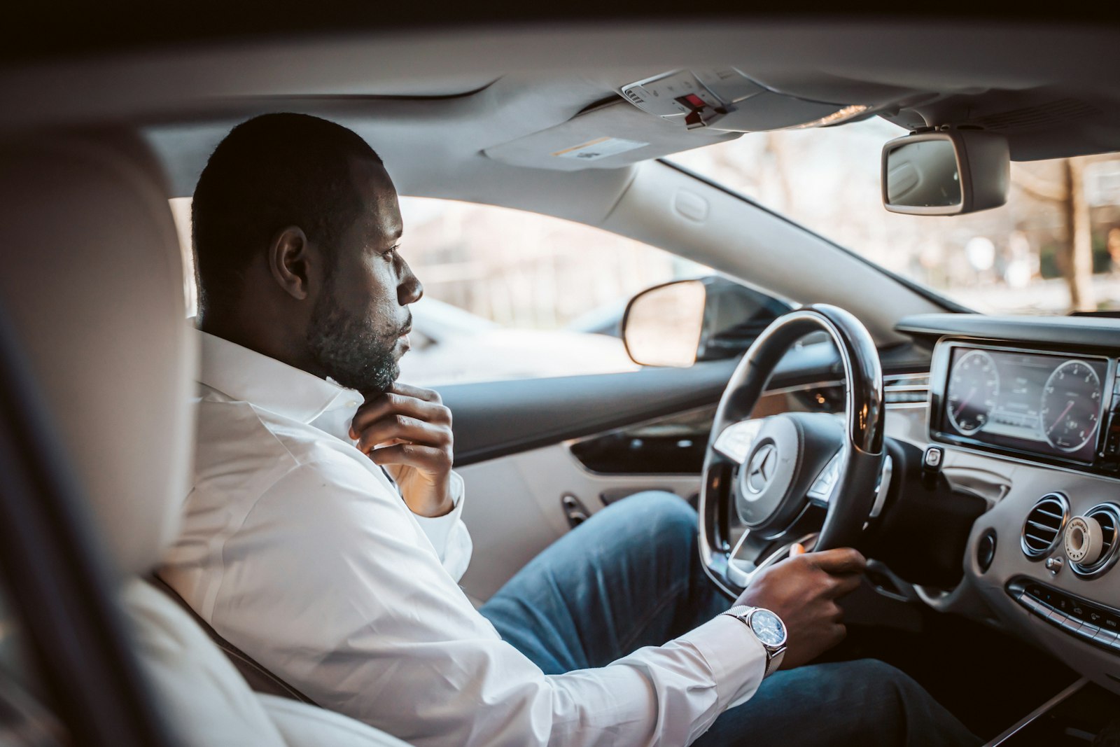 A driver in a white shirt at the wheel of a smart car